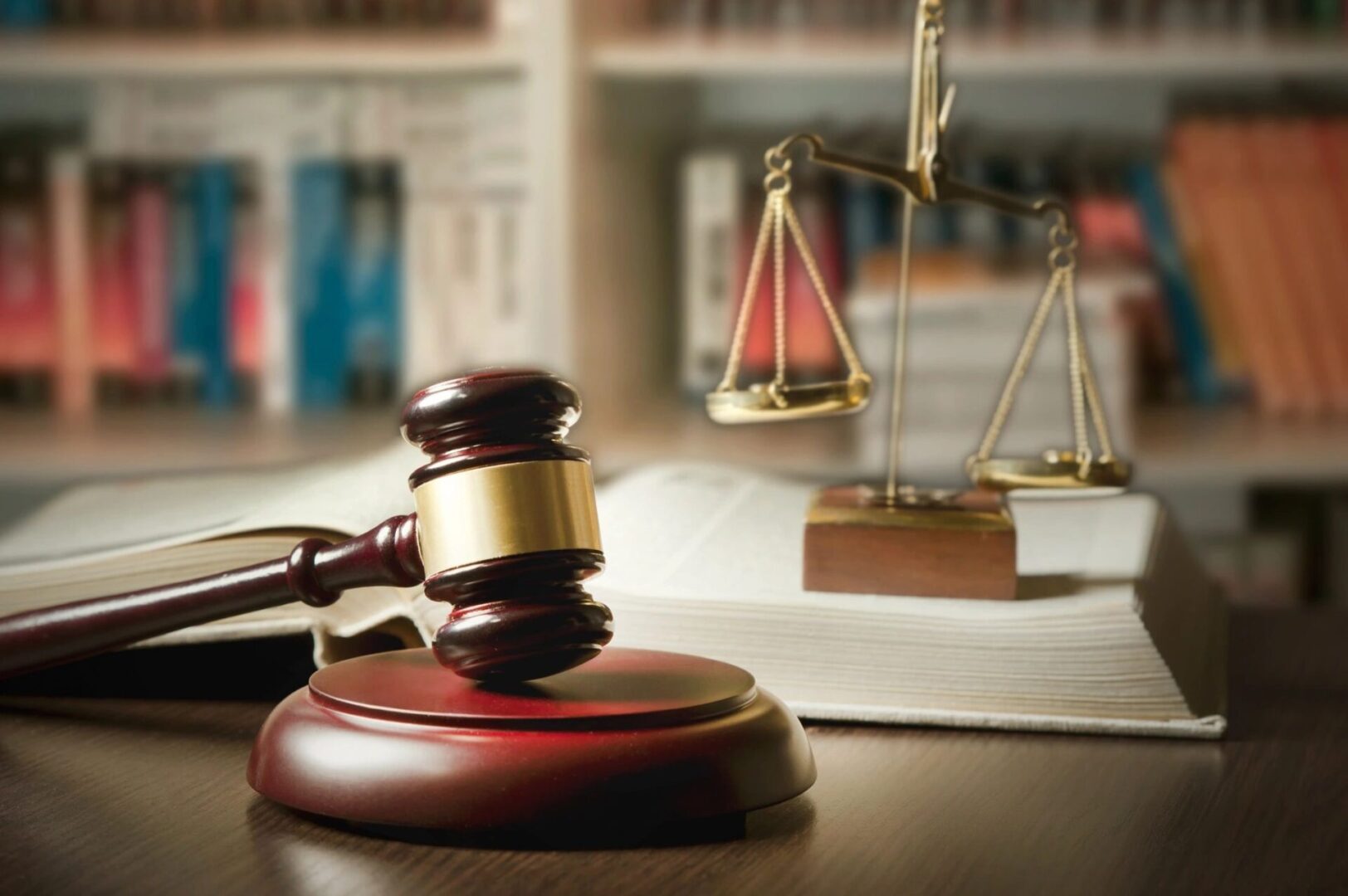 A judge 's gavel and scale in front of a law book.