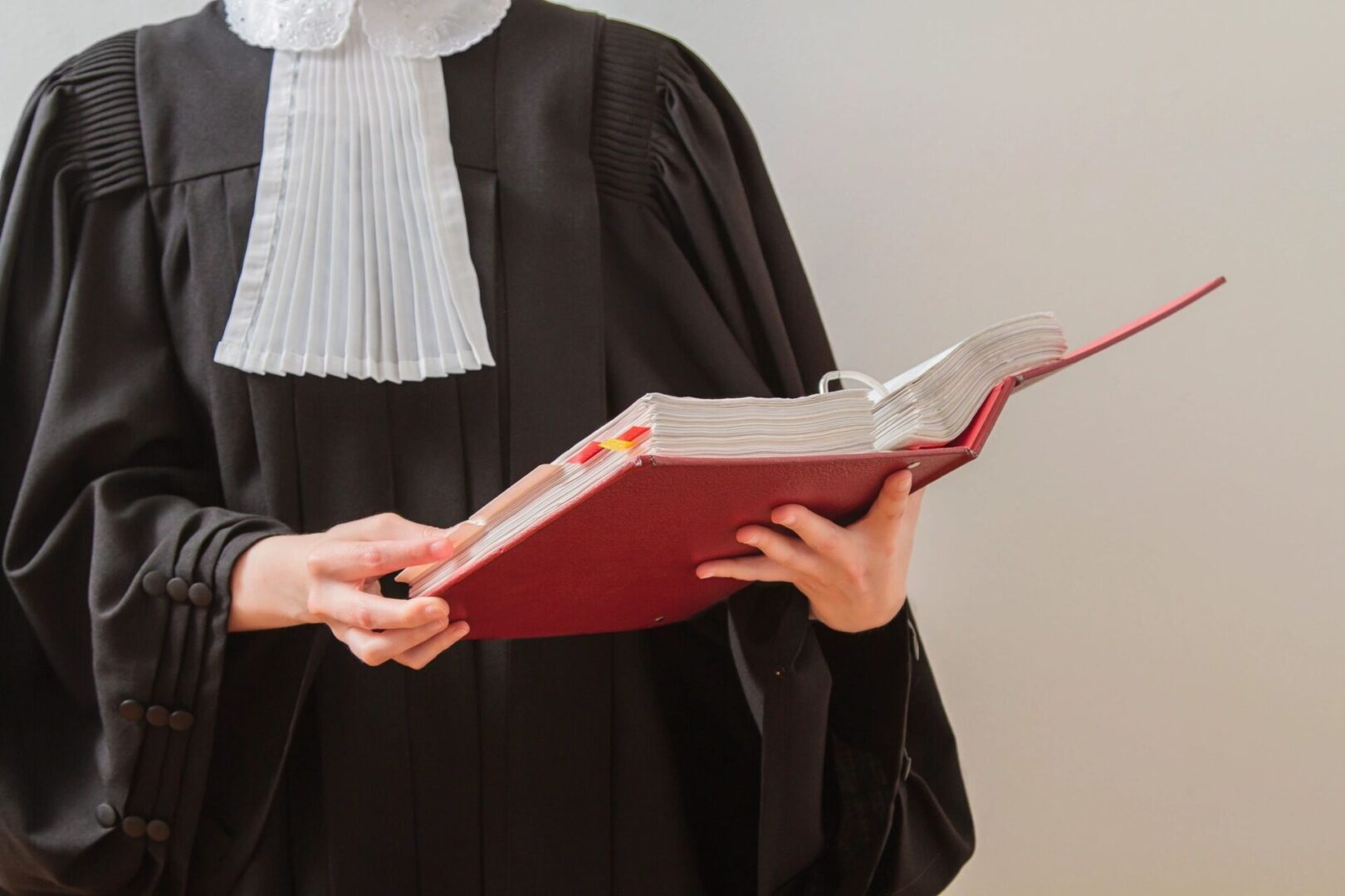 A person in black robe holding red book