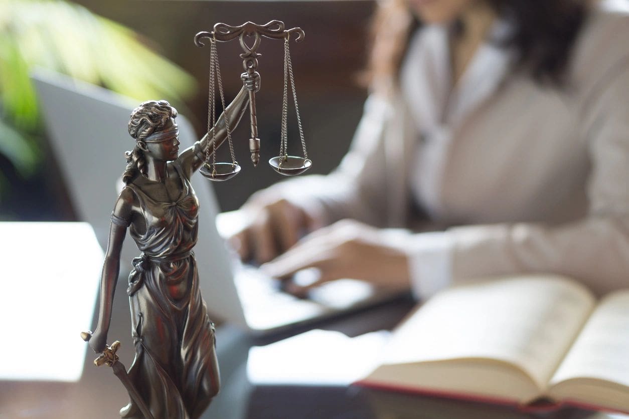 A statue of justice and two people in the background.