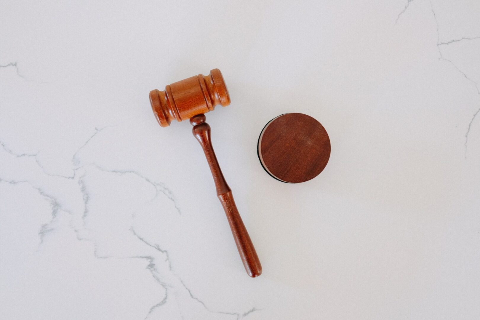 A wooden gavel and coin on top of white counter.