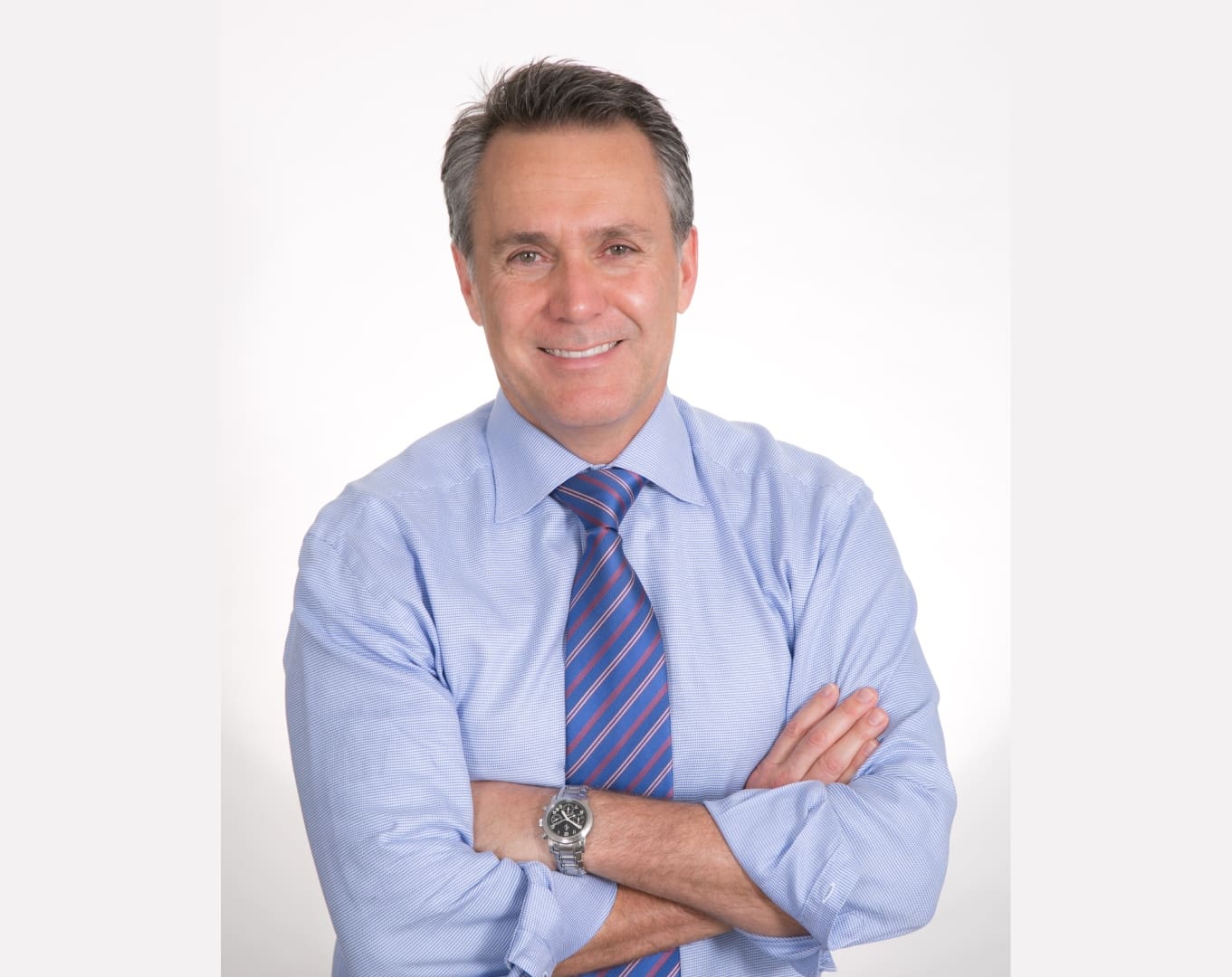 A man in a blue shirt and tie with his arms crossed.